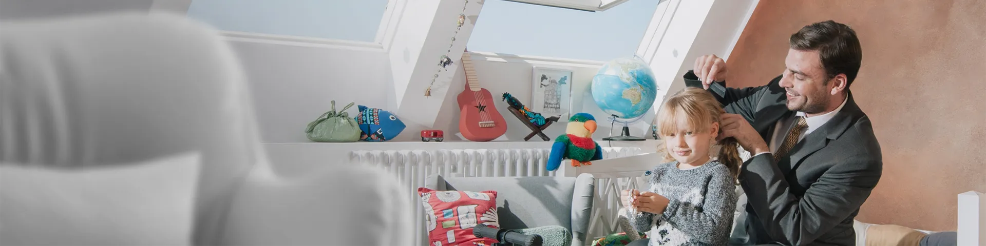 A father dressed to go to work combs the hair of his daughter before shcool.