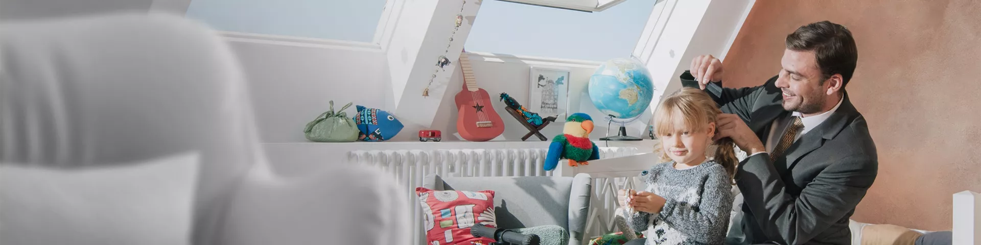 A father dressed to go to work combs the hair of his daughter before shcool.