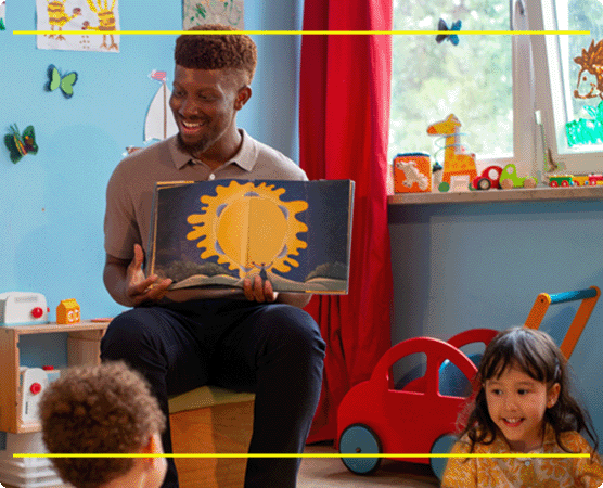 A male teacher reading stories from a book in kindergarten kids.