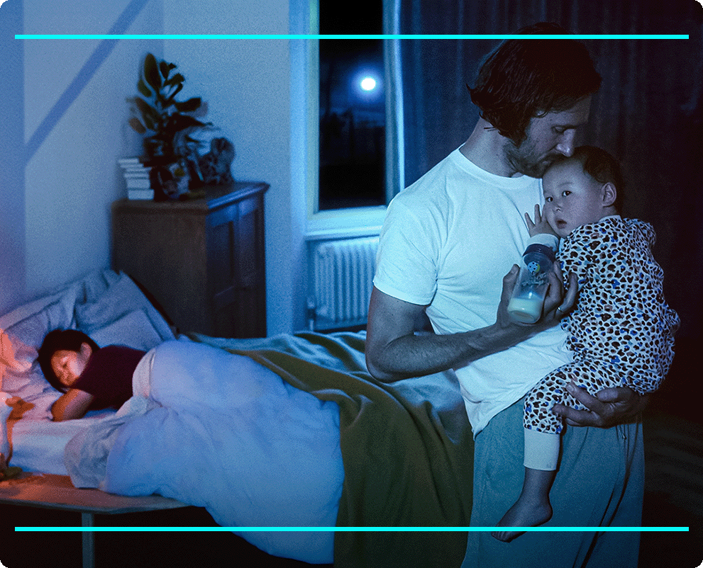 Father feeding kid while mother is sleeping