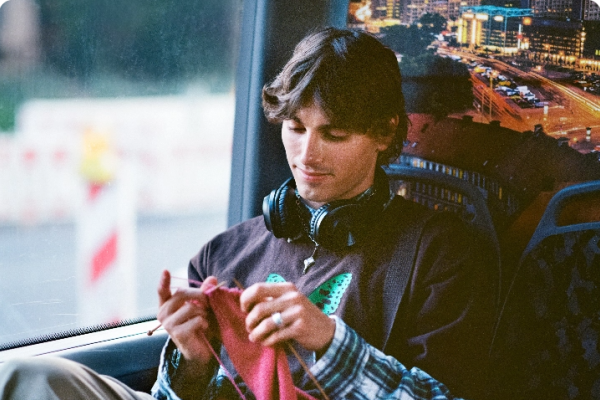 A boy knitting in a bus